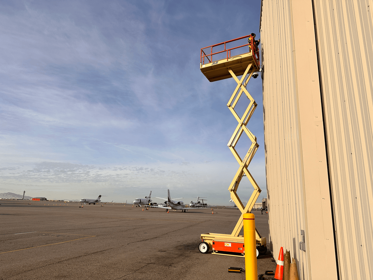 LVEC technician on a scissor lift installing a camera on an airport hangar
