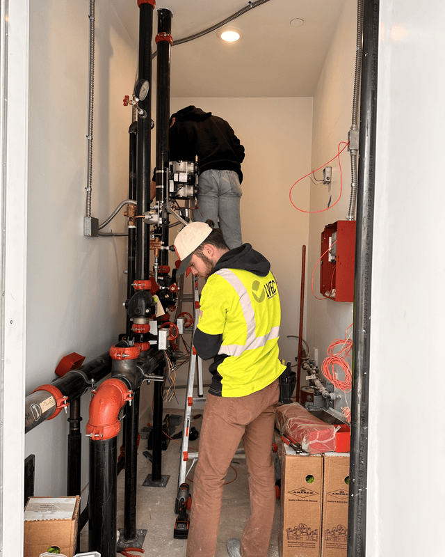 Two LVEC technicians working in a fire sprinkler riser room