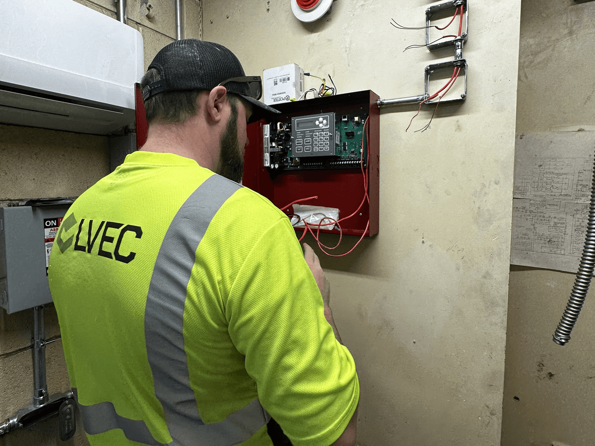LVEC technician wiring a fire alarm control panel