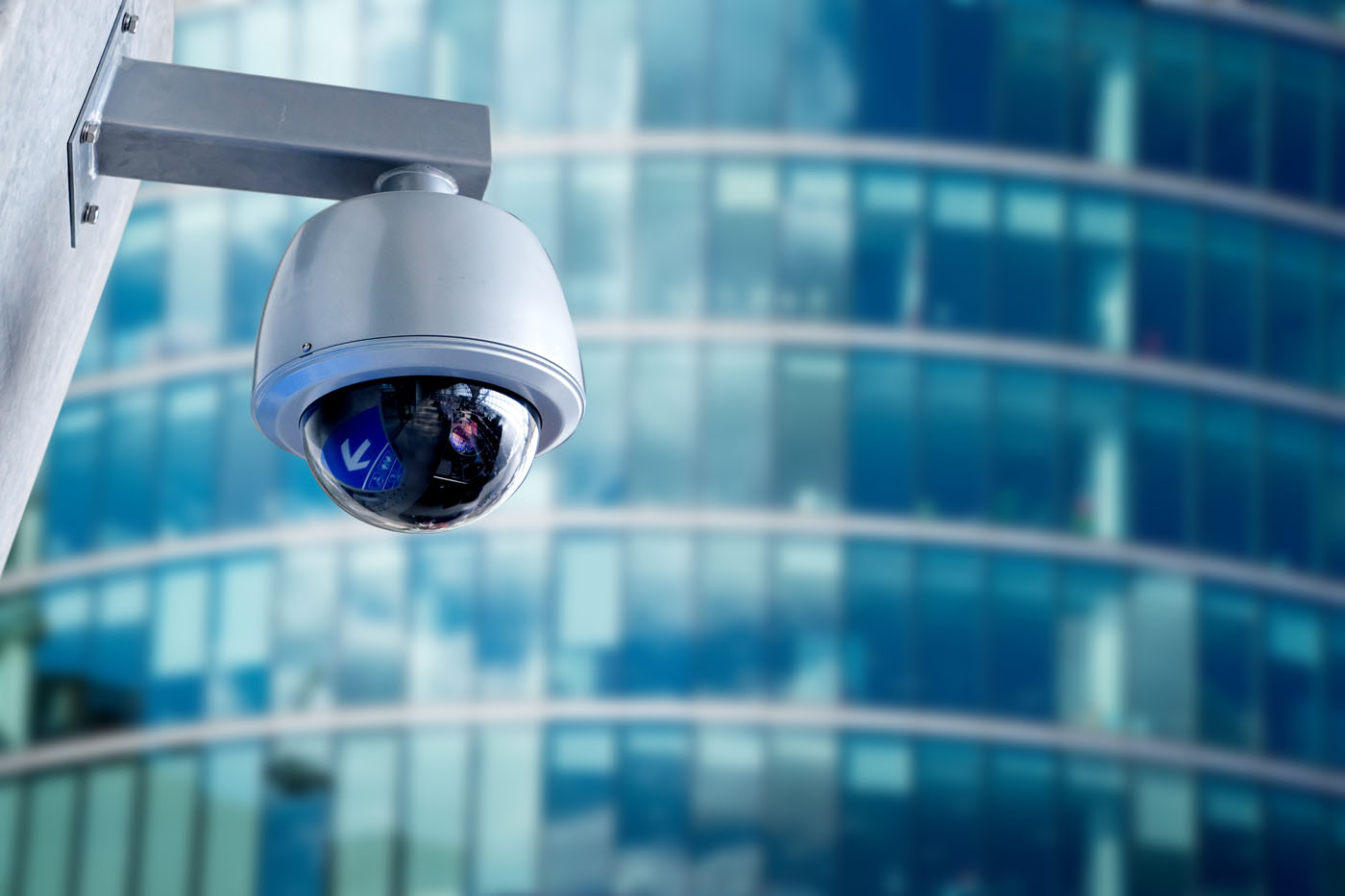 A bulb security camera outside a glass building, contact LVEC for a security camera for business installation.