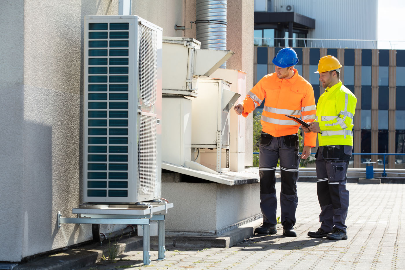 Two LVEC technicians installing a fire and safety device outside a business.